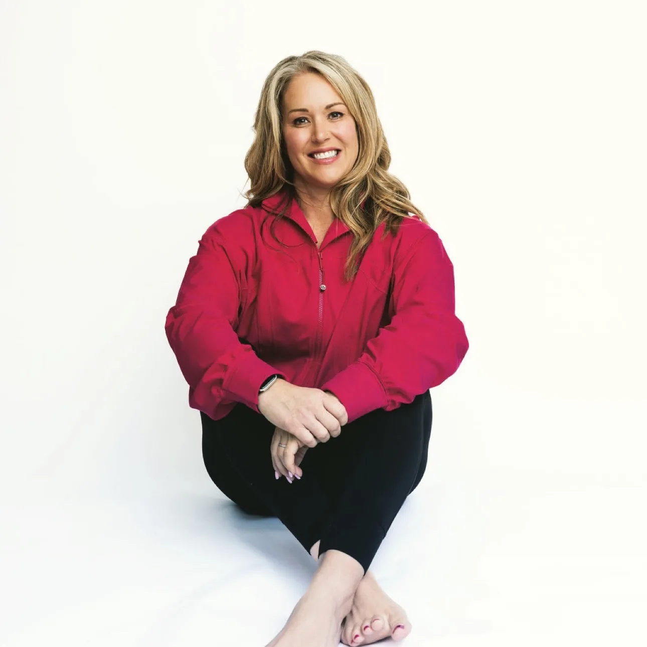Kate Thomas, sitting cross-legged and smiling, in a photograph